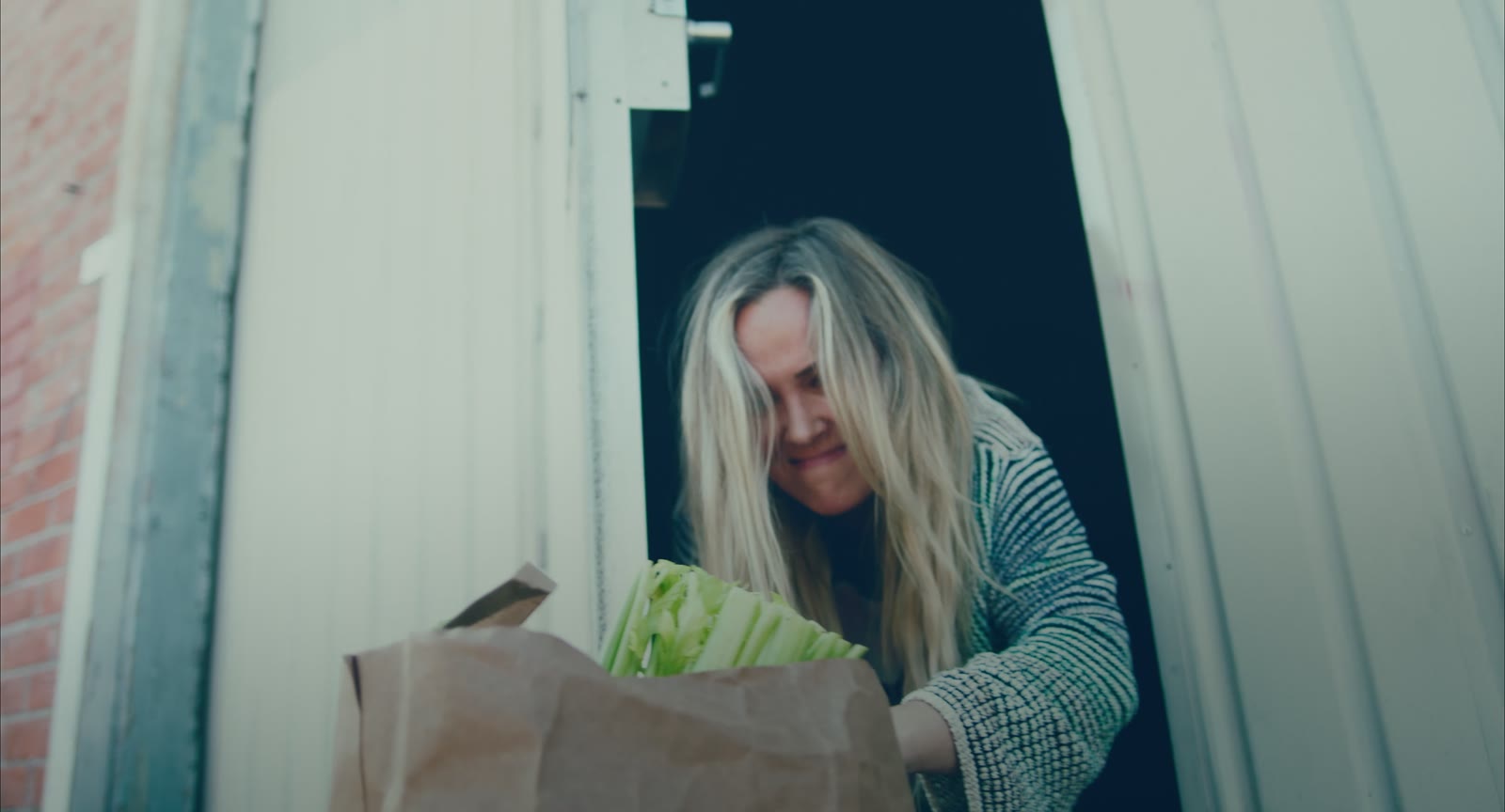 Juniper peeking out of the building's side entrance with her groceries